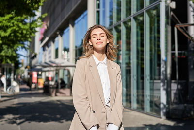 Portrait of young woman standing in city