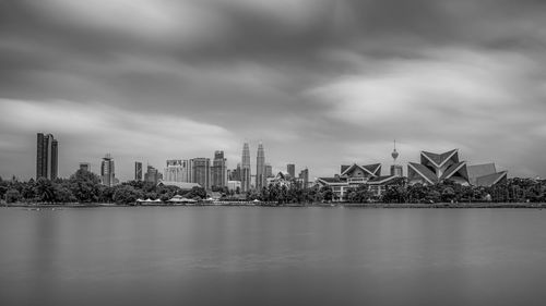 River and buildings against cloudy sky