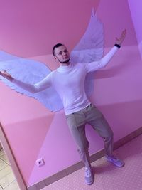 Full length portrait of woman dancing against pink wall