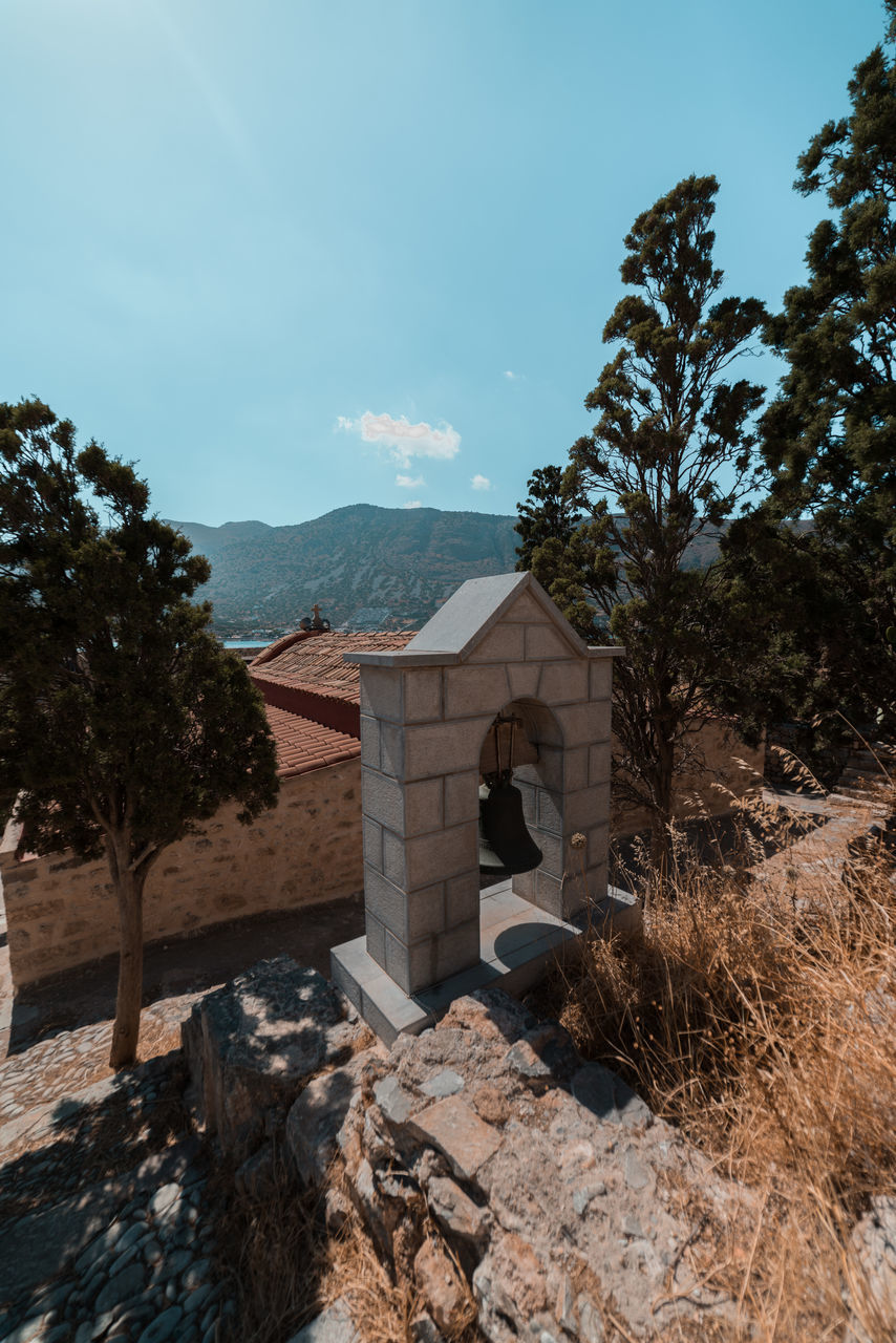 HOUSES AND TREES BY ROCKS AGAINST SKY