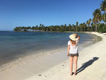 Rear view of young woman standing at beach