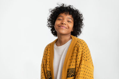 Portrait of young woman standing against white background