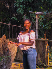 Portrait of young woman standing against trees