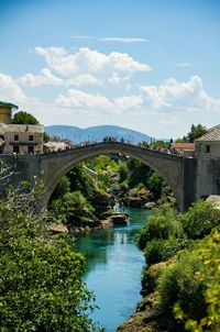 Arch bridge over river against sky