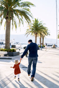 Rear view of mother and daughter on palm tree