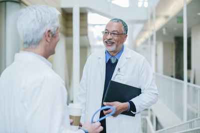 Male doctors talking while standing in hospital corridor