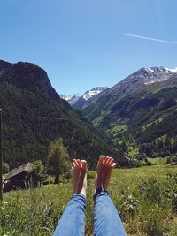 Low section of person on mountain against blue sky