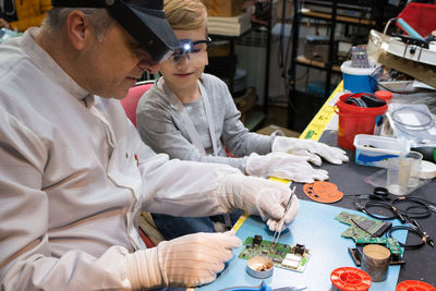 Grandfather and boy repairing computer part on table at home