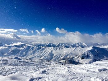 Snow covered landscape against blue sky