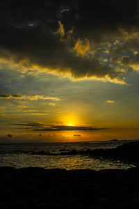 Scenic view of sea against dramatic sky during sunset