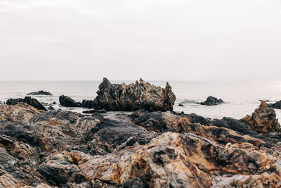 Rock formation on beach against sky