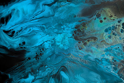 Fluid art. blue abstract waves with golden particles on black background. marble effect background