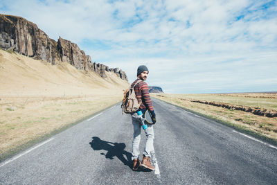 Man with umbrella on road against sky