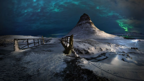 Scenic view of snow covered mountain against cloudy sky at night