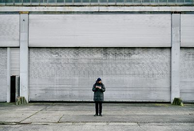 Man standing on footpath against building