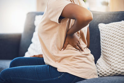 Midsection of woman sitting on sofa at home