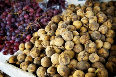 Lanzones on sale at a market with grapes