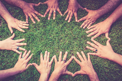 Cropped hands of friends on grass