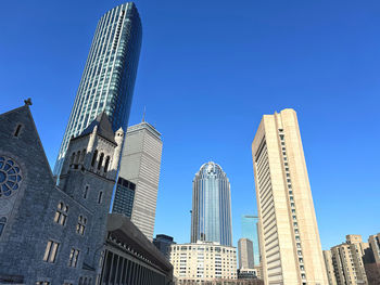 Low angle view of skyscrapers against clear blue sky