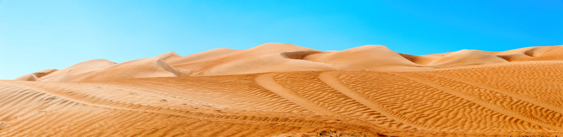 Sand dunes in desert against clear blue sky