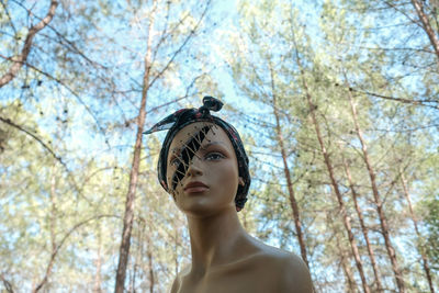 Low angle view of lifeless female model standing against bare tree