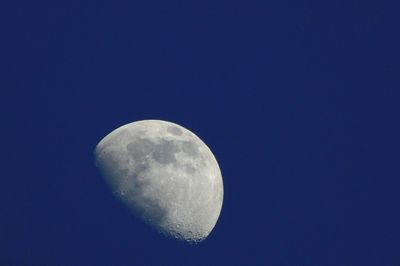 Low angle view of half moon against clear blue sky