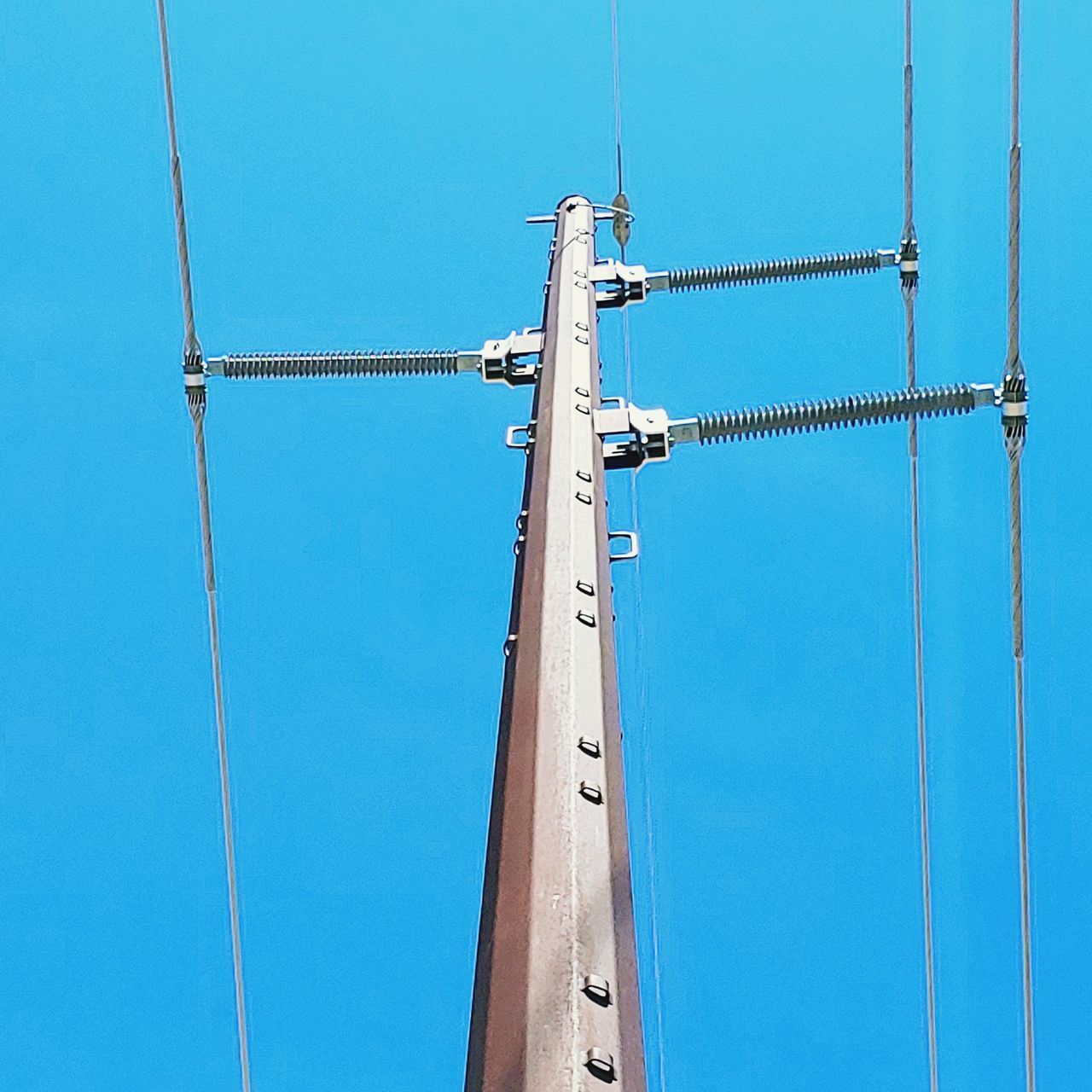 LOW ANGLE VIEW OF CRANES AGAINST BLUE SKY