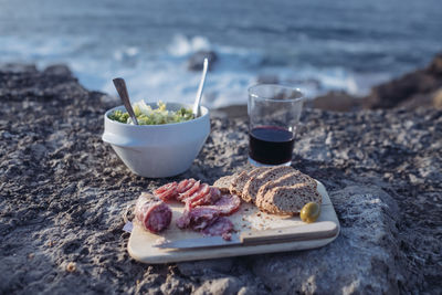 Food on cutting board by drink at beach