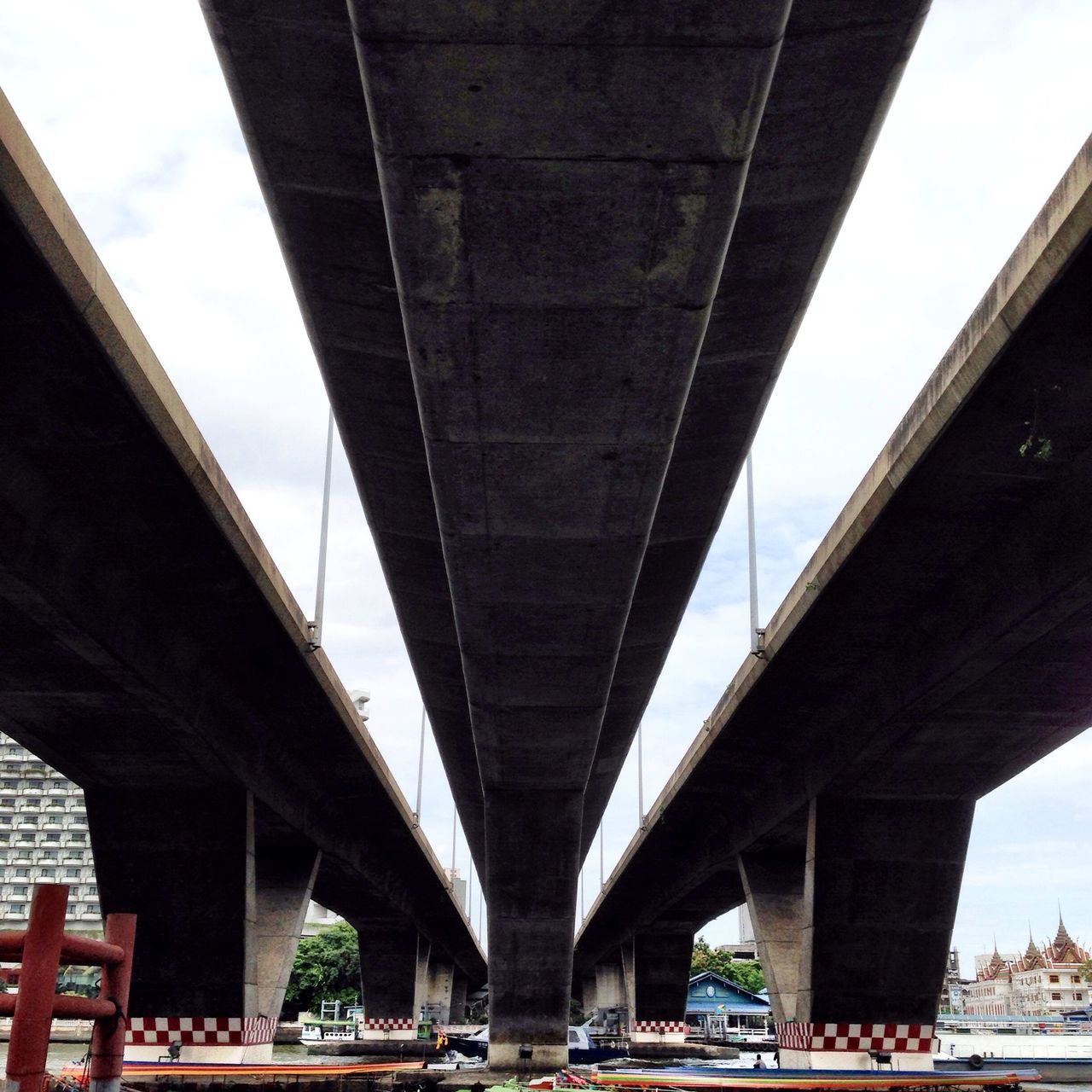 architecture, bridge - man made structure, built structure, connection, engineering, transportation, bridge, low angle view, suspension bridge, city, river, sky, building exterior, architectural column, arch, travel destinations, famous place, travel, international landmark, car