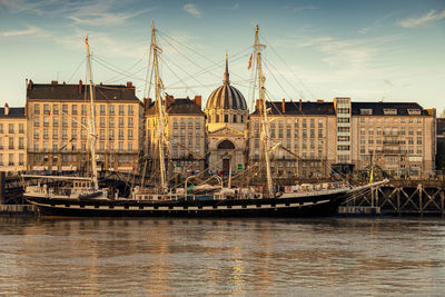 Sailboats in river with city in background