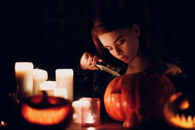Young woman carving pumpkin in dark