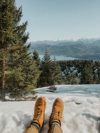 Low section of person on snowcapped mountain against sky