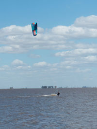 Person paragliding in sea against sky