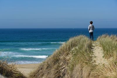 Rear view of man looking at sea against sky