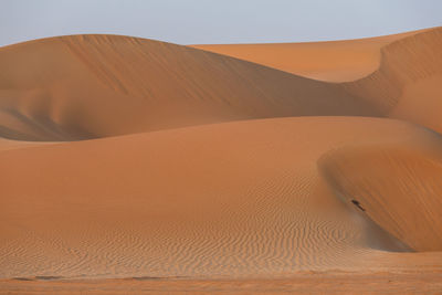 Sand dunes in desert against clear sky