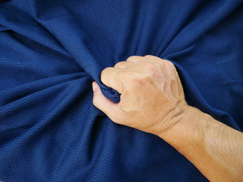 Cropped hand holding crumpled bed sheet