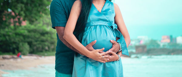 Midsection of woman standing against blue sea