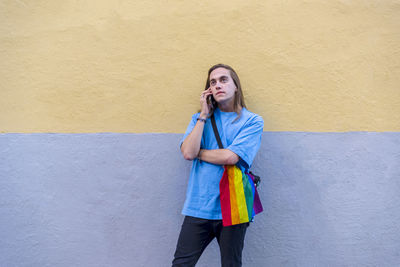 Man talking on the phone while wearing a belt bag with the lgbt rainbow flag.