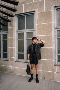 Full length of young woman standing against building