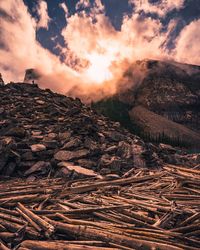 Wood on land by mountains against sky during sunset
