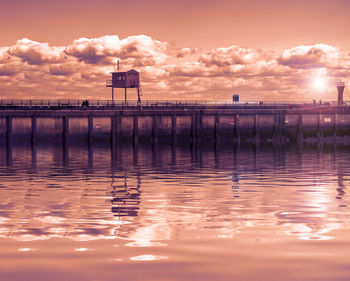 House on pier over sea against sky during sunset