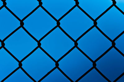 Full frame shot of chainlink fence against clear blue sky