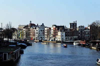 Canal amidst buildings in city against clear sky