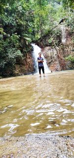 Man in river amidst trees in forest