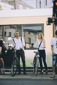 Businessman and businesswoman with bicycle crossing road in city