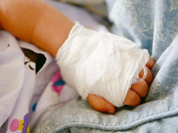 Cropped hand of baby with physical injury on bed