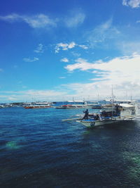 Sailboats moored on sea against blue sky