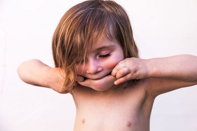 Close-up of girl stretching mouth against white wall