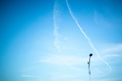 Low angle view of vapor trails in blue sky