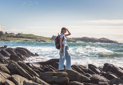 Rear view of woman standing at beach against sky